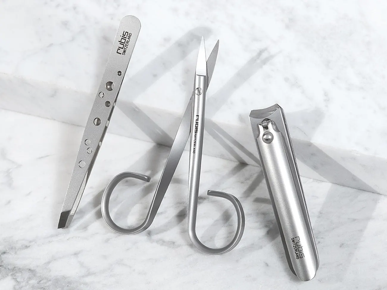 Rubis tweezers, scissors and nail clipper in stainless steel on marble
